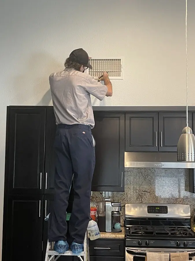 Technician inspecting an air vent during HVAC service in Excelsior Springs